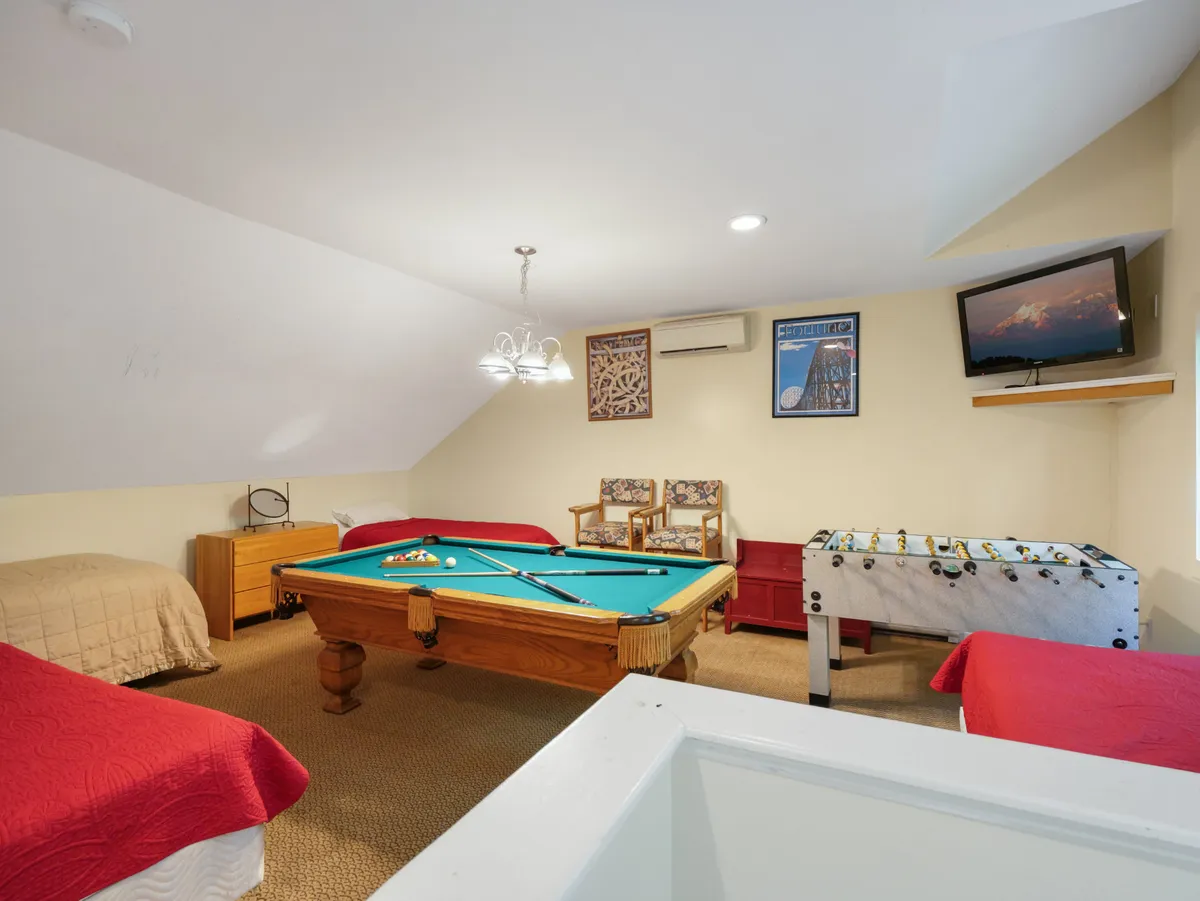 A lively game room featuring a pool table and foosball table as the main attractions. There is also a seating area and a television, creating an environment perfect for both active play and relaxation. The space comfortably accommodates groups for games, watching TV, or socializing.